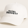 White cap with 'HOTEL BENNETT' text on a light beige background